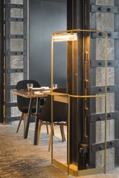 a table and chair in a room with metal bars on the walls, along with a large mirror