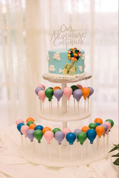 a three tiered cake with colorful balloons on it