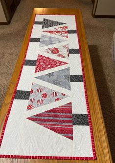 a table runner made with red, grey and white quilts