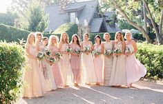 a group of women standing next to each other in front of a tree and bushes