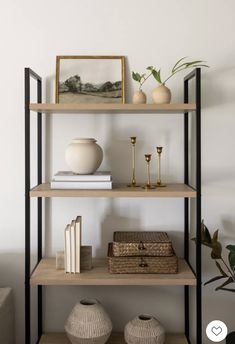 three shelves with vases, books and other items on them in a white room