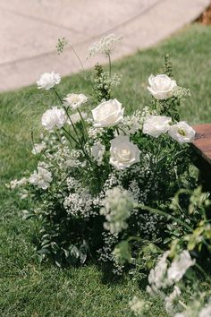 white flowers are in the grass near a bench