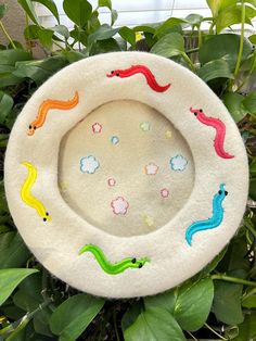 a close up of a plant with plants in the background and a white plate with colorful designs on it