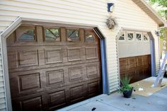 two brown garage doors are open in front of a white house