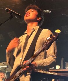 a man with a guitar standing in front of a microphone