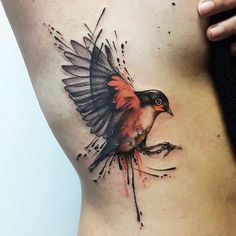 a bird tattoo on the side of a woman's lower back, with blood splatters all over it