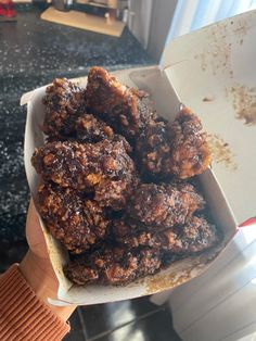 a person holding a box full of fried food