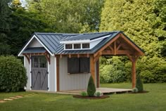 a small shed in the middle of a grassy area with trees and bushes around it