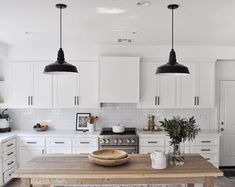 a kitchen with white cabinets and black pendant lights over the island in front of an oven