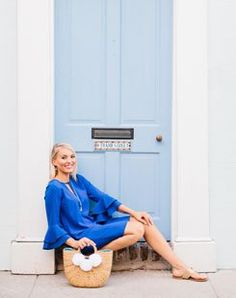 a woman sitting in front of a blue door