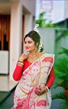 a woman in a red and white sari posing for the camera with her hand on her hip