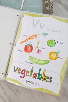 an open notebook with vegetables drawn on it and the words vegatables written in cursive writing