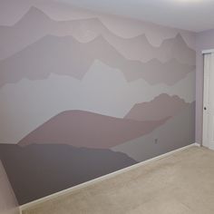 an empty room with a painted mountain mural on the wall and door to another room