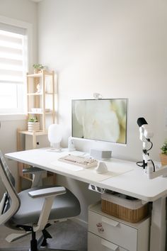 a white desk with a computer monitor and keyboard sitting on it's side in front of a window