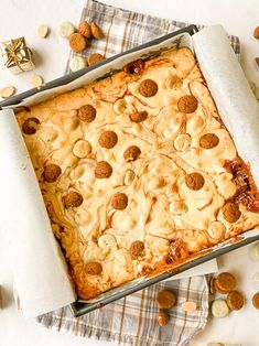 a square pizza in a pan on a table with nuts and other food items around it