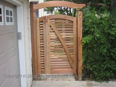 a wooden gate is open on the side of a house