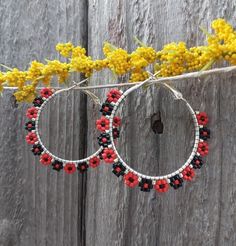 red and black beaded hoop earrings hanging from a branch with yellow flowers in the background