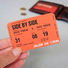 a hand holding an orange ticket for side by side