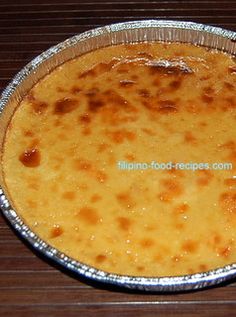 a pie sitting on top of a wooden table next to a pan filled with cheese