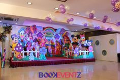 a stage set up with balloons and mickey mouse characters on it for a birthday party