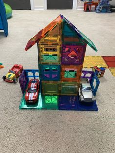 a toy house made out of plastic with cars around it