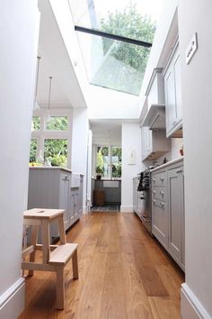 an open kitchen with wooden floors and skylight above the stove top oven, along with stainless steel appliances