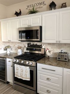 a kitchen with white cabinets and stainless steel stove top oven in the middle of it