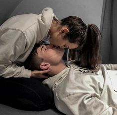 a man and woman kissing on top of each other while sitting in front of a bookshelf