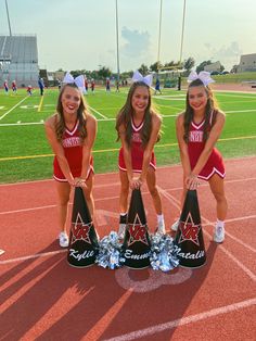 three cheerleaders posing with their trophies on the field