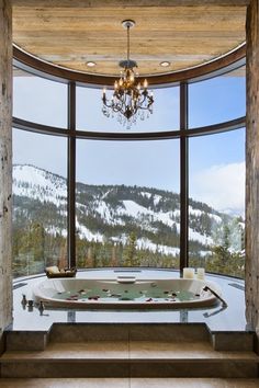 a bathroom with a large window and a tub in front of a mountain view is shown