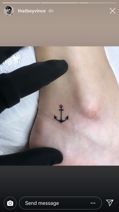 a small anchor tattoo on the side of a woman's foot, with an arrow in