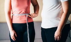 two people standing next to each other with a measuring tape on their waist and hands