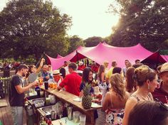 a group of people standing around a wooden table with drinks and pineapples on it