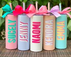 four personalized tumbles with bows on them sitting in front of some plants and bushes