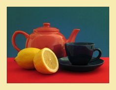 there is a teapot, cup, and lemons on the red tablecloth