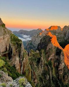 the mountains are covered in bright orange light and some clouds above them, as the sun sets