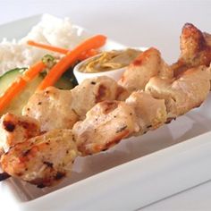 chicken skewers with vegetables and rice on a plate