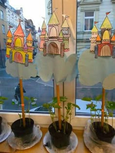 three potted plants in front of a window with paper cutouts on the windowsill