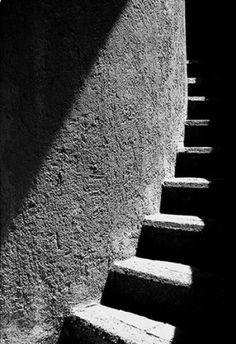 black and white photograph of steps leading up to a building with shadows on the wall