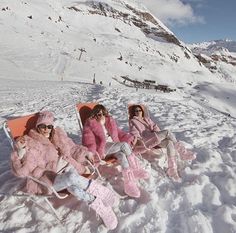 three women in pink coats sitting on snow covered ground