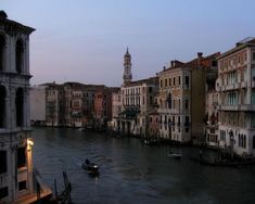 a boat traveling down a river next to tall buildings on either side of the water