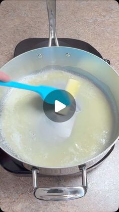 a frying pan filled with white liquid and a blue spatula on top of it