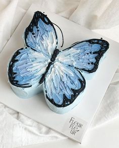 a blue butterfly cake sitting on top of a white sheet