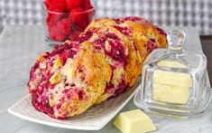 raspberry scones on a plate next to butter and strawberries