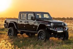 a black jeep is parked in the middle of a field at sunset or sunrise,