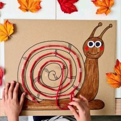 a child's hand is drawing a snail on a piece of paper