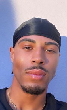 a close up of a person wearing a black shirt and headband with a blue wall in the background