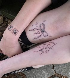 two people sitting on the ground with tattoos on their legs