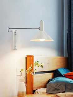 a lamp that is on top of a wooden table next to a bed with blue sheets