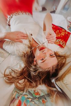 a woman laying on top of a bed with scissors in her hand and hair flying through the air